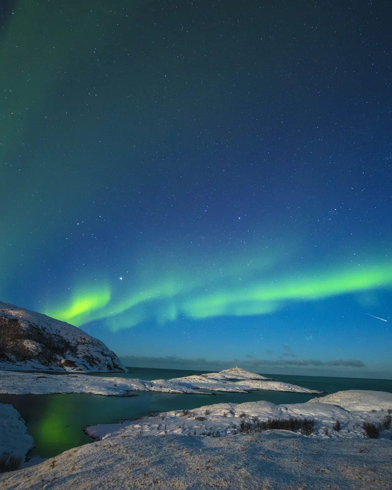 Un’aurora verde illumina il cielo stellato sopra Tromsø.