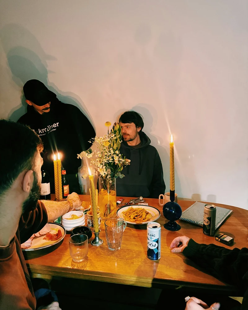 Amici riuniti intorno a una tavola illuminata da candele.