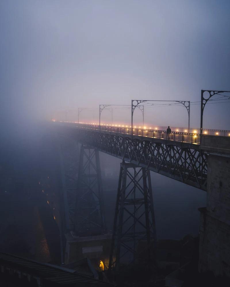 Ponte illuminato che scompare nella nebbia al crepuscolo.